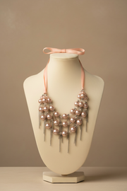 Collana statement rosa con elementi effetto perla e catene decorative indossata su busto